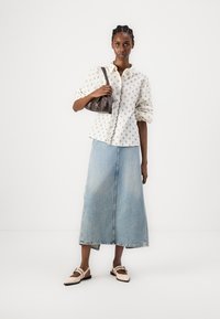 Vit skjorta med blommönster, ljusblå denim-maxikjol, brun läderhandväska och beige ballerinas. Släta texturer, avslappnad design.