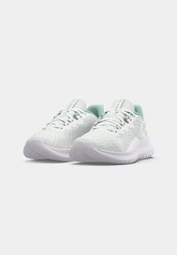 White athletic shoes with a textured upper, mint green accents, and a thick white sole, featuring a lace closure and supportive design.