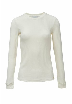 Top de manga larga acanalado en color crema, con cuello redondo y detalles decorativos de perlas en los puños. Textura suave y diseño ajustado.