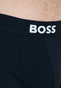 Schwarze Boxershorts mit einer weichen Textur, featuring einen breiten Bund, der mit "BOSS" in weißen Großbuchstaben bedruckt ist.
