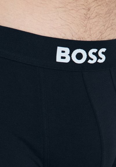 Boxers noirs avec une texture douce, dotés d'une large ceinture marquée du mot "BOSS" en lettres majuscules blanches.