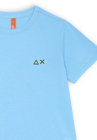 T-shirt azzurro chiaro a maniche corte realizzato in morbido cotone. Presenta un piccolo motivo ricamato verde (triangolo e 'X') nella parte sinistra del petto.