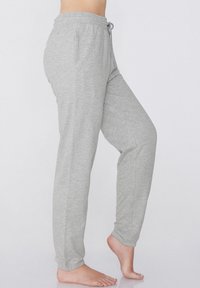 Pantalones de chándal de color gris claro, fabricados en un tejido suave, con una cintura elástica y cordón, bolsillo laterales y piernas ajustadas.
