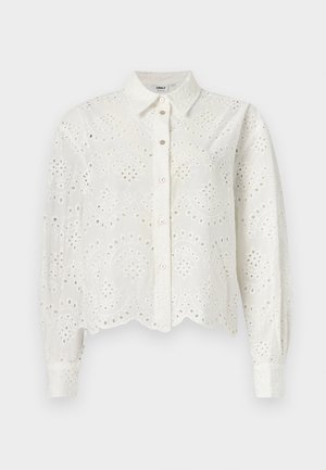 Biela košeľa s dlhými rukávmi zapínaná na gombíky, so vzorom vyrezávaných kvetov a zvlneným lemom, vyrobená z ľahkej, textúrovanej tkaniny.