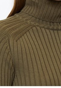 Olivově zelený rolák svetr s žebrovanou texturou, výraznými svislými liniemi a přiléhavým střihem kolem krku.