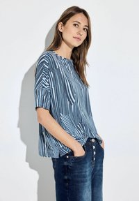 Blauw gestreept short-sleeve shirt met een relaxte pasvorm. Zachte stof, brede halslijn en abstract patroon met variërende tinten blauw en marineblauw.
