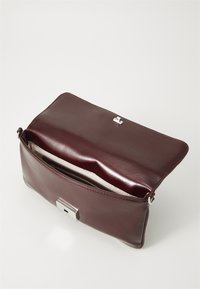 Sac à main en cuir bourgogne avec un fermoir en métal argenté, design plat, ouverture sur le dessus et doublure intérieure crème. Comprend une poche zippée à l'intérieur.