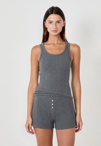 Conjunto de top de tirantes ancho y pantalones cortos de color gris con un diseño ajustado. El top tiene tirantes anchos; los pantalones cortos presentan tres botones en la parte frontal. Textura suave.
