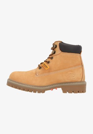 Botas de tobillo de ante beige con acentos marrones, ojales de metal y una suela de goma con un dibujo robusto. Logo visible en el lado.