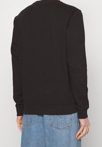 Felpa nera in cotone con scollatura e polsini a coste, caratterizzata da una vestibilità comoda e un design minimalista. Tessuto uniforme senza motivi.