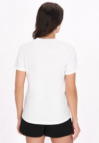 Hvid t-shirt med korte ærmer og rund halsudskæring, glat stof og oprullede ærmer, parret med sorte shorts. Enkelt, afslappet design.