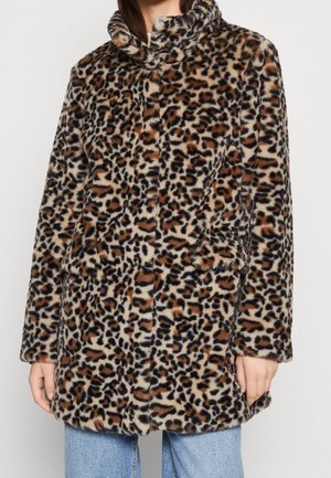 Frau trägt einen midilangen, langärmeligen Kunstpelzmantel mit Leopardenmuster, hohem Kragen und vorderen Taschen.