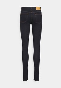 Smala jeans i mörkblå denim, med en beige etikett vid midjan, kontrasterande sömmar och femficksdesign med standard bakfickor.