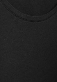 Tuvplāns melnas apkakles audumam, kurā redzami detalizēti šuvumu un tekstūras elementi.