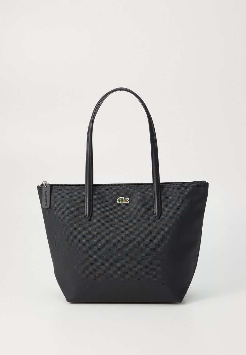 Sac fourre-tout noir texturé avec deux poignées, fermeture éclair et petit logo crocodile vert au centre avant.