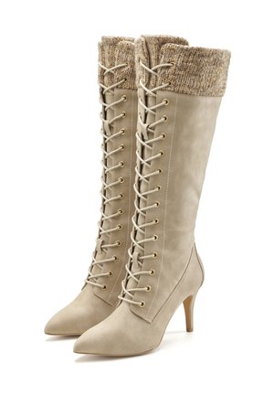 Beige leather thigh-high boots with a knitted tan cuff, pointed toe, and gold eyelets, featuring a lace-up design and 4-inch stiletto heel.
