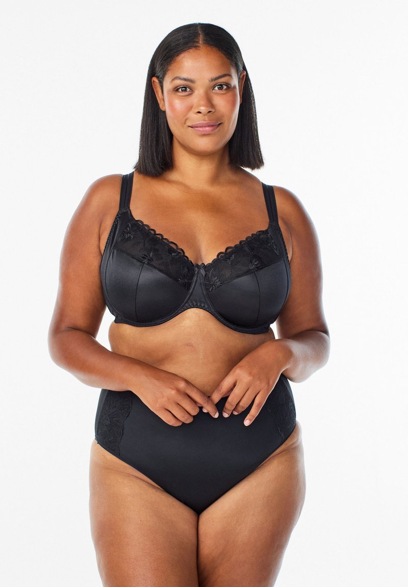 Melna krūštura ar mežģīņu akcentiem un polsterētām kausēm, ar regulējamiem siksniņām un viļņotu apdari. Apvienots ar augsta jostasvieta melnā apakšveļā.