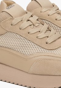 Beige sneakers met mesh panelen en suede accenten, voorzien van een gevoerde zool en getextureerde veters voor een veilige pasvorm.