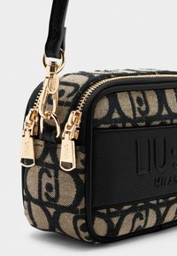 Borsa testurizzata nera e beige con un compartimento con zip, caratterizzata da un motivo distintivo e hardware in tono oro, inclusi dettagli con logo.