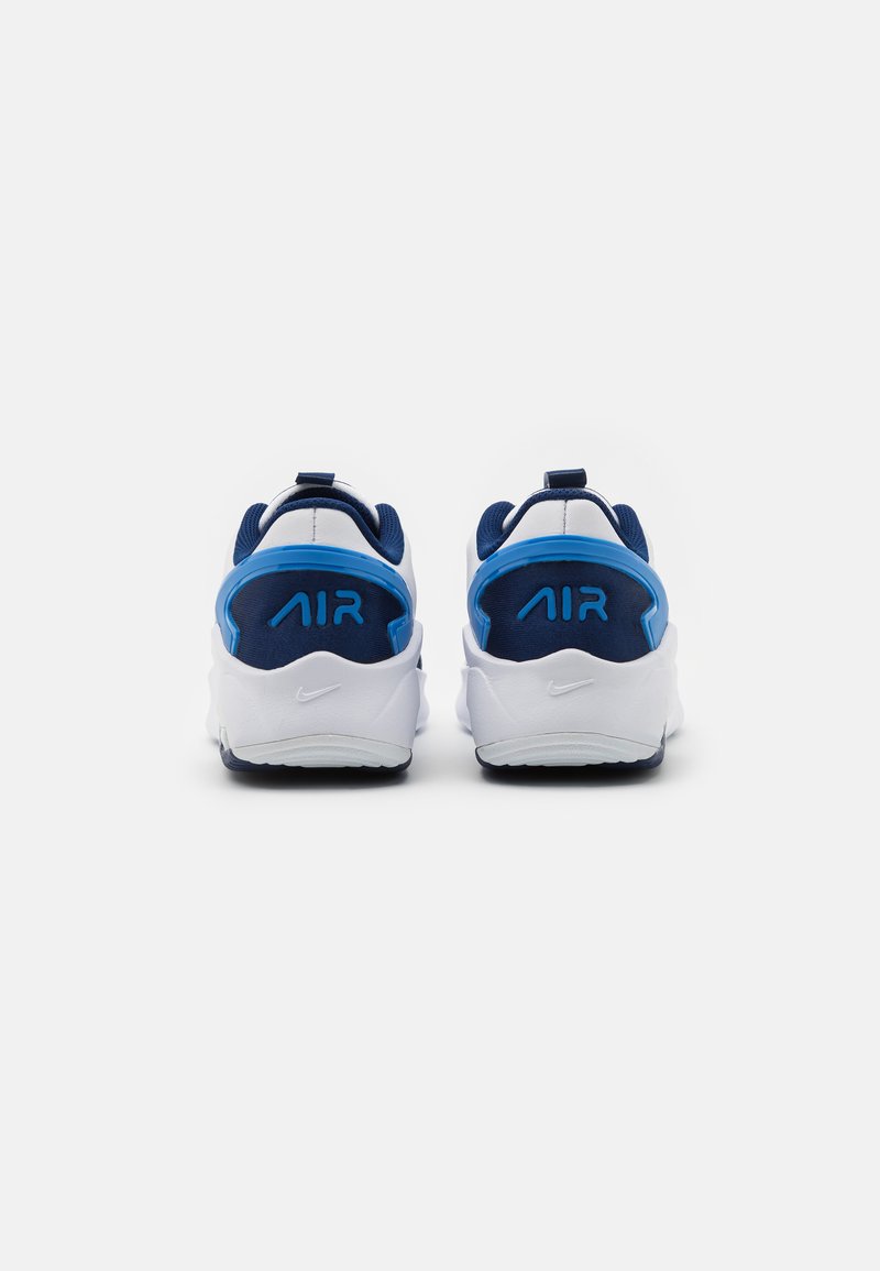 Zapatillas blancas y azules con tacones redondeados, que presentan una parte superior texturizada, logo "AIR" en azul en la parte trasera y una suela de goma.
