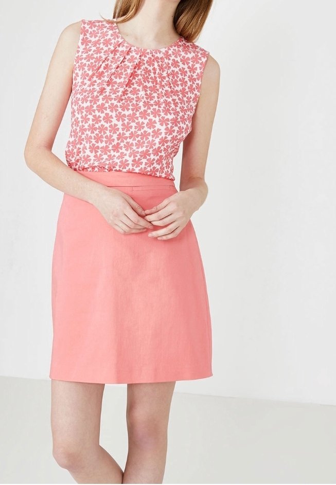 Floral-patterned sleeveless top in pink and white, paired with a solid coral skirt. Smooth texture, with pleat detailing at neckline.
