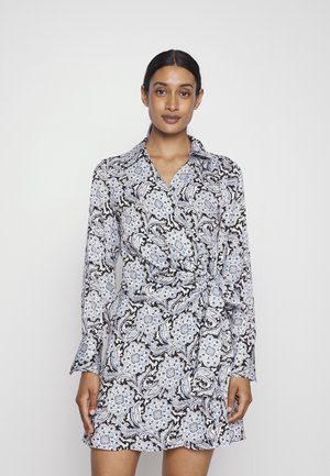 Vestido envolvente com padrão preto e branco, detalhes florais azuis, mangas longas e gola; o tecido parece suave e leve.