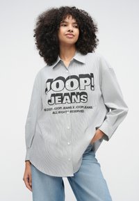 Ριγέ πουκάμισο με κουμπιά σε γκρι και λευκό, με εντυπωσιακό γραφικό "JOOP! JEANS." Άνετη εφαρμογή με κλασικό γιακά και χαλαρή ραφή στους ώμους.