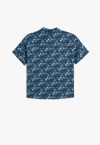 Camisa de manga corta en tejido azul marino con un patrón de palmeras y barcos en blanco y azul claro, con un dobladillo recto y un diseño de cuello clásico.