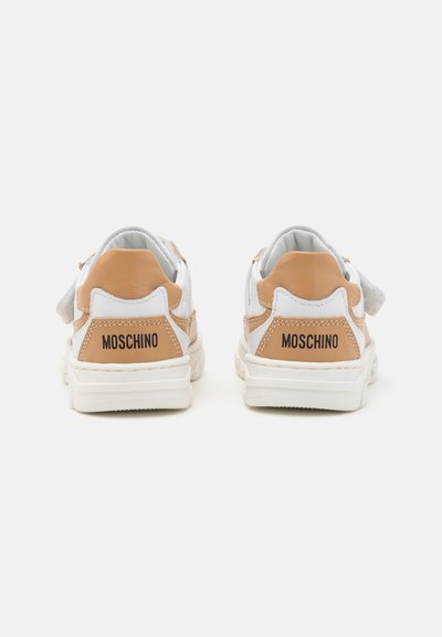 Baltās kedas ar brūniem akcentiem un melnu "MOSCHINO" logotipu aizmugurē. Ir mīksts apkakles apdare un teksturēta gumijas zole.