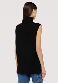 Černý bezrukávový svetr s vysokým límcem, ribbovanou texturou a postranními rozparky na lemu, navržený v uvolněném střihu.