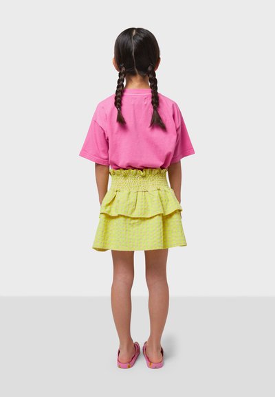 Pink cotton T-shirt, layered yellow gingham skirt with smocked waist, worn with pink slip-on shoes, viewed from the back.