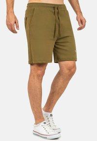 Pantaloni corti in cotone verde oliva con vita elastica e cordoncino, dotati di due tasche laterali e un taglio dritto.