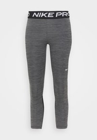 Leggings de sport gris avec une ceinture noire arborant le texte « NIKE PRO » en blanc. Le matériau semble lisse et légèrement texturé.