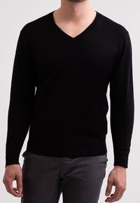 Schwarzer V-Ausschnitt-Pullover mit langen Ärmeln, aus einem weichen Material gefertigt. Verfügt über eine figurbetonte Passform sowie gerippte Bündchen und Saum.