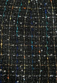 Tissu noir texturé avec des fils colorés et des sequins. Présente un motif en grille créé par des lignes contrastées de différentes couleurs.