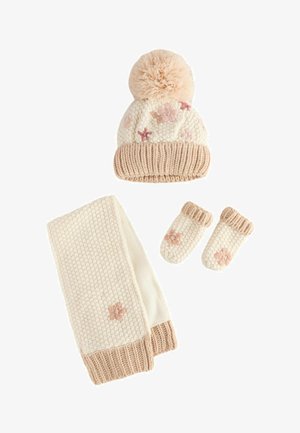 Strik vinterhat i crème og beige med en stor pompon på toppen, der har lyserøde stjernemønstre og øreklapper. Ideel til koldt vejr.
