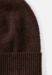Bonnet en tricot marron foncé en laine douce, doté d'un poignet côtelé et d'un corps lisse et texturé, offrant chaleur et confort.