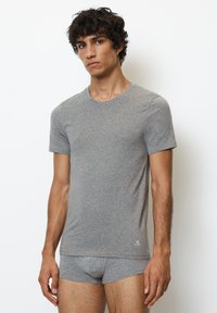Grijze katoenen T-shirt met korte mouwen en een ronde hals, gecombineerd met bijpassende grijze aansluitende slips. Minimalistisch ontwerp met een logo-detail.