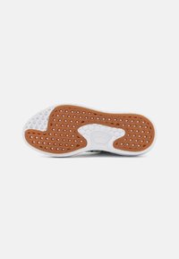 Semelle de sneaker en caoutchouc blanc, surface texturée et motifs hexagonaux brun clair. Présente un design incurvé avec des éléments de traction distincts.