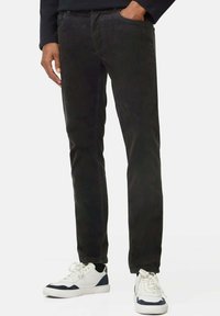 Zwarte katoenen stretchjeans met een slim fit, vijf-pocket ontwerp en een lichte vervaging, gecombineerd met witte en marineblauwe sneakers.