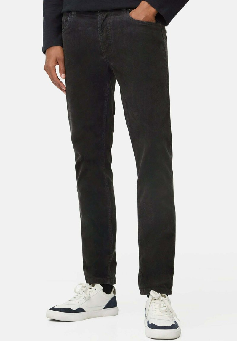 Zwarte katoenen stretchjeans met een slim fit, vijf-pocket ontwerp en een lichte vervaging, gecombineerd met witte en marineblauwe sneakers.