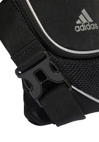 Čierna taška Adidas s textúrovanou látkou, sieťovanými detailmi, nastaviteľným pásikom s čiernou plastovou prackou a odrazovým lemovaním.