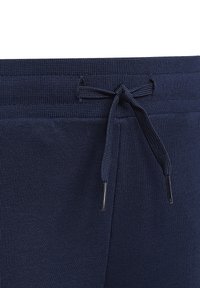 Pantaloni da sudore blu navy con fascia in vita caratterizzata da una texture a coste, un cordino regolabile con punte metalliche e aperture rinforzate.