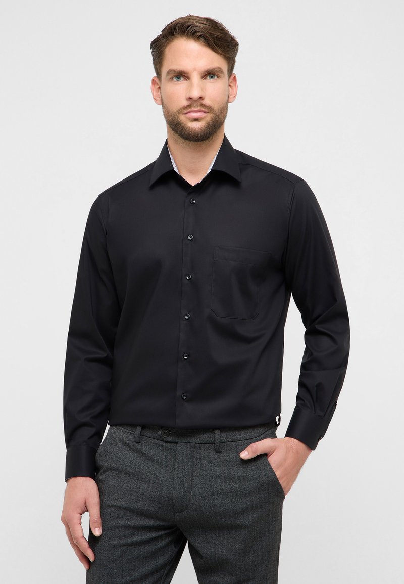 Zwart overhemd met knopen, een gestructureerde kraag, een enkele borstzak en gladde stof. Gecombineerd met grijze, patterned broek.