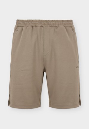 Pantalones cortos beige con cintura elástica, bolsillos laterales, pequeñas aberturas a los lados y un sutil logo "BOSS" en el muslo derecho.