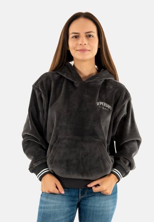 Grijze corduroy hoodie met een voorzak, trekkoordcapuchon en wit logo. Beschikt over zwart-witte gestreepte boorden. Casual fit.