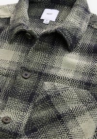 Chemise en laine à col avec motif à carreaux géométriques noir et gris et boutons, taille moyenne étiquetée de la marque NEXT.