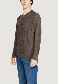 Maglione marrone a maniche lunghe con un motivo logo tonale. Presenta un collo a girocollo e polsini a costine, abbinato a jeans in denim blu.