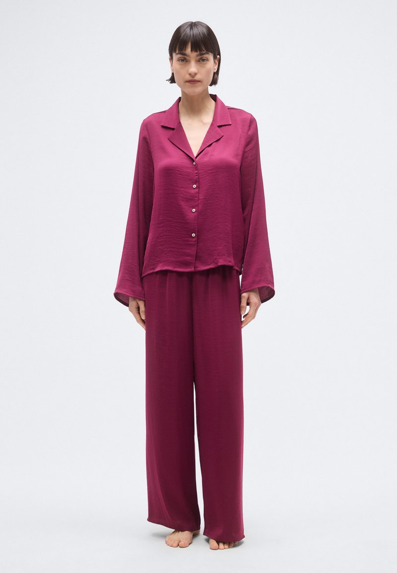 Ensemble de pyjama bordeaux en satin léger, comprenant un haut boutonné à col et un pantalon amples, avec des manches longues et une silhouette décontractée.