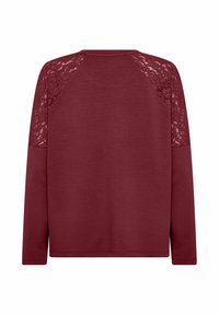 Burgundy long-sleeve top featuring a solid body, lace detailing on raglan sleeves, and a round neckline. Soft texture with a relaxed fit.